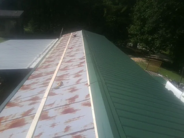 Old rusted panels beside newly installed green metal roofing — Wind Damage Roof Repair by Roofing Brothers in Ocklawaha