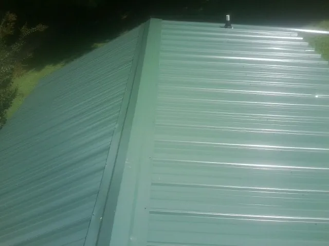 New green metal panels meeting at the ridge of a roof — Flat Roof Repair work by our crew in Ocklawaha