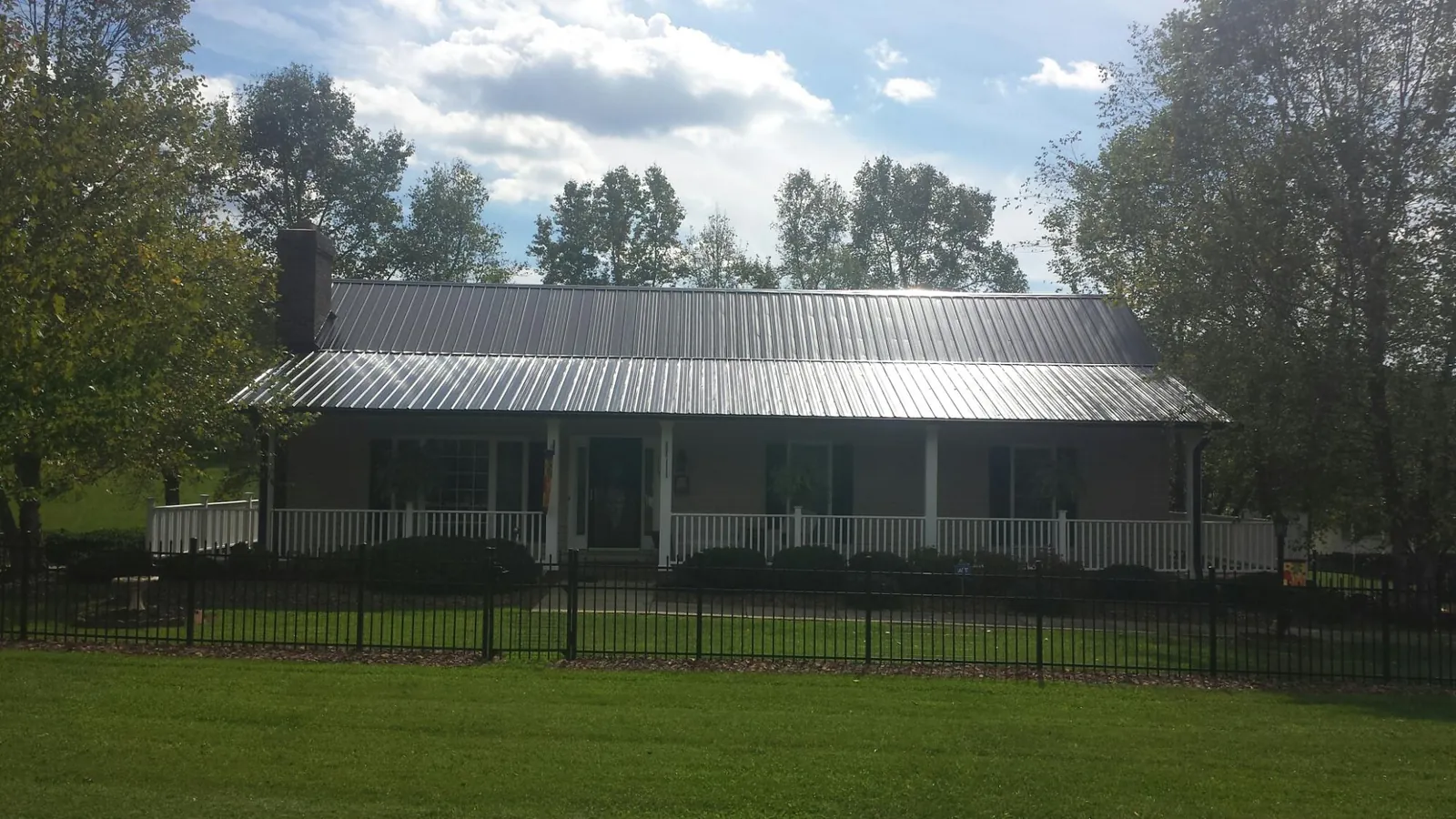 Gray metal roof on a brick ranch with a full width front porch — Gutter Guard Installation work by our crew in Ocklawaha